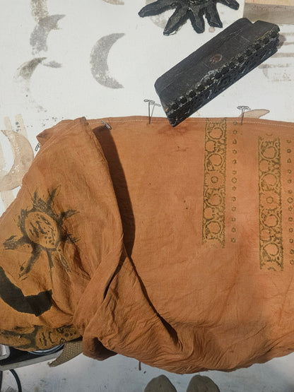 Brown fabric with decorative patterns on a white surface with tools.