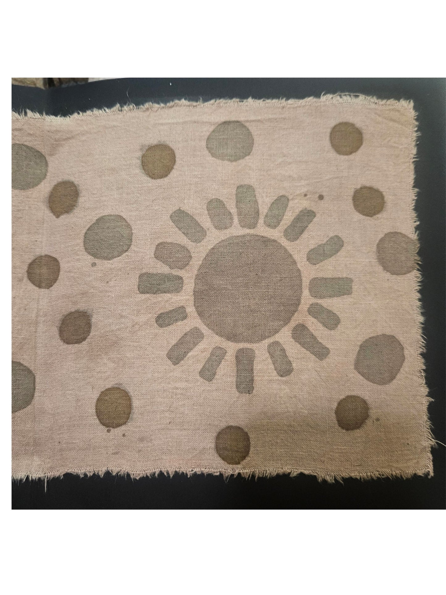 Textile with sun design and dot patterns on a plain background