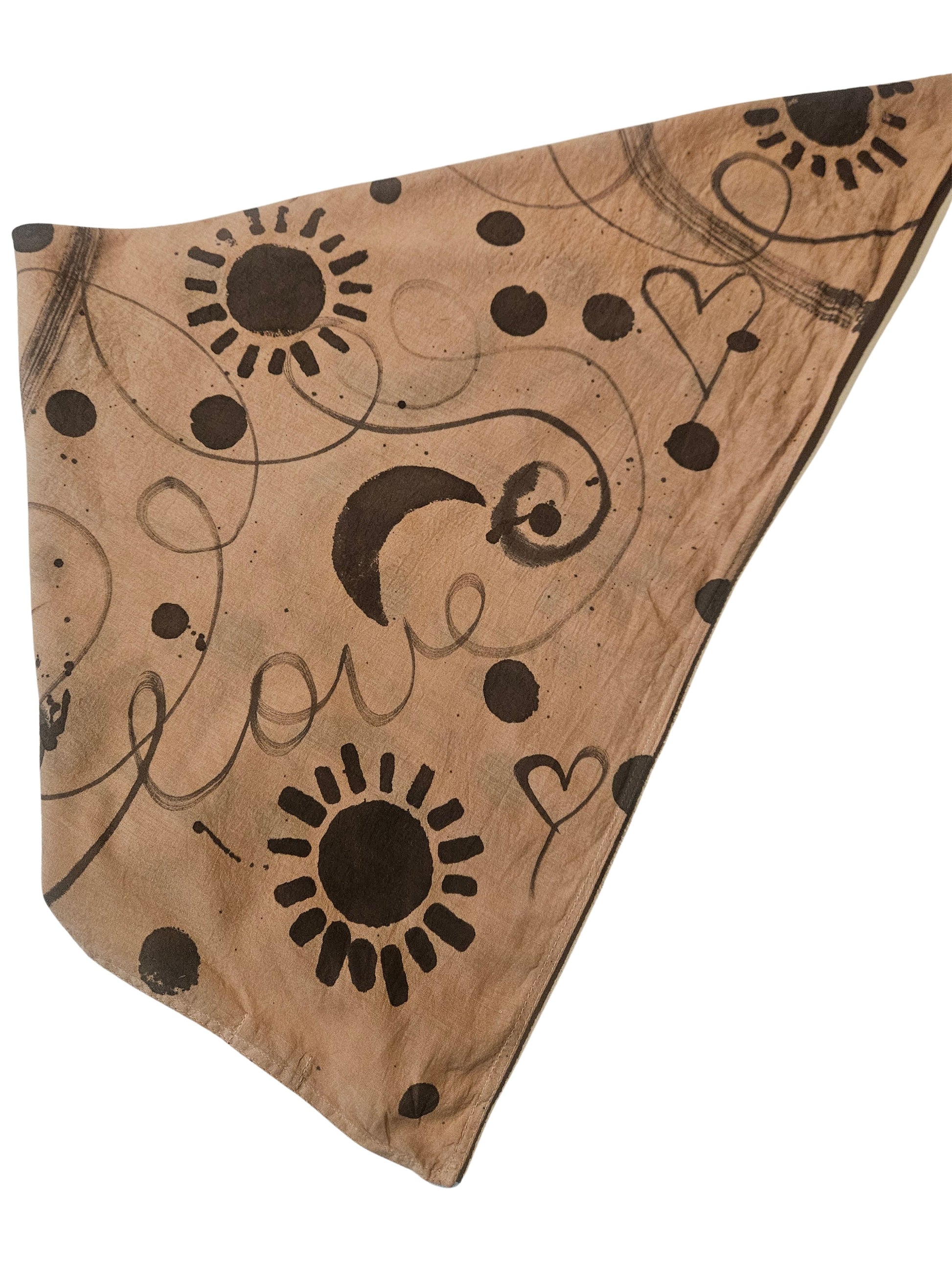 Triangle-shaped fabric with sun, moon, and heart patterns on a brown background