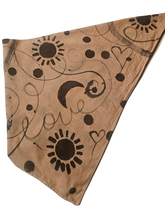 Triangle-shaped fabric with sun, moon, and heart patterns on a brown background